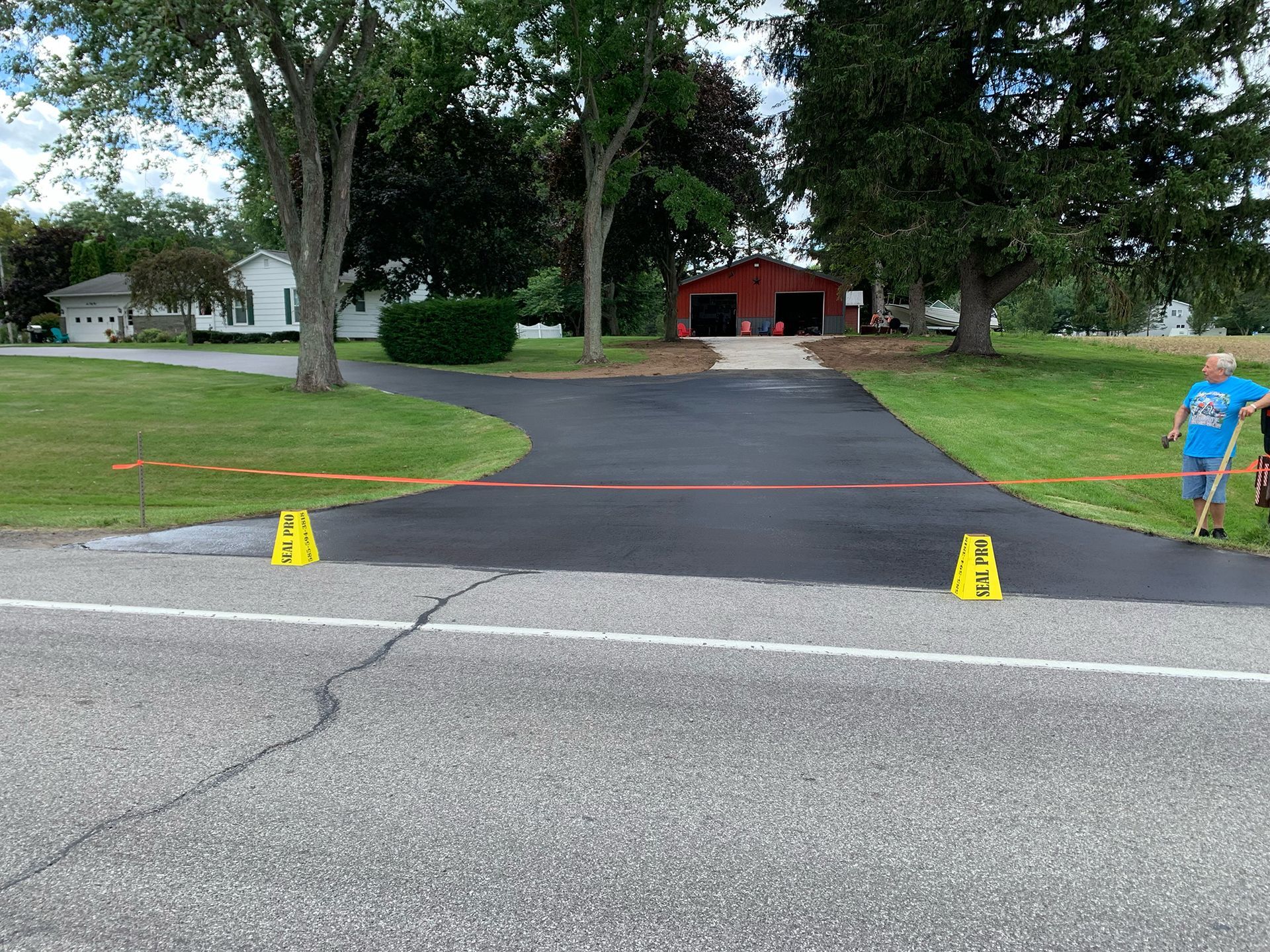 a man in a blue shirt is walking down a paved driveway