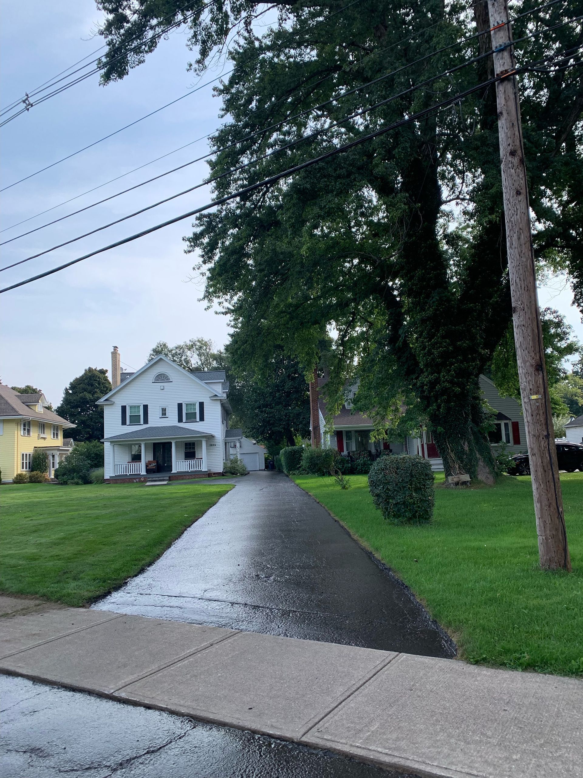 a driveway leading to a white house in a residential neighborhood