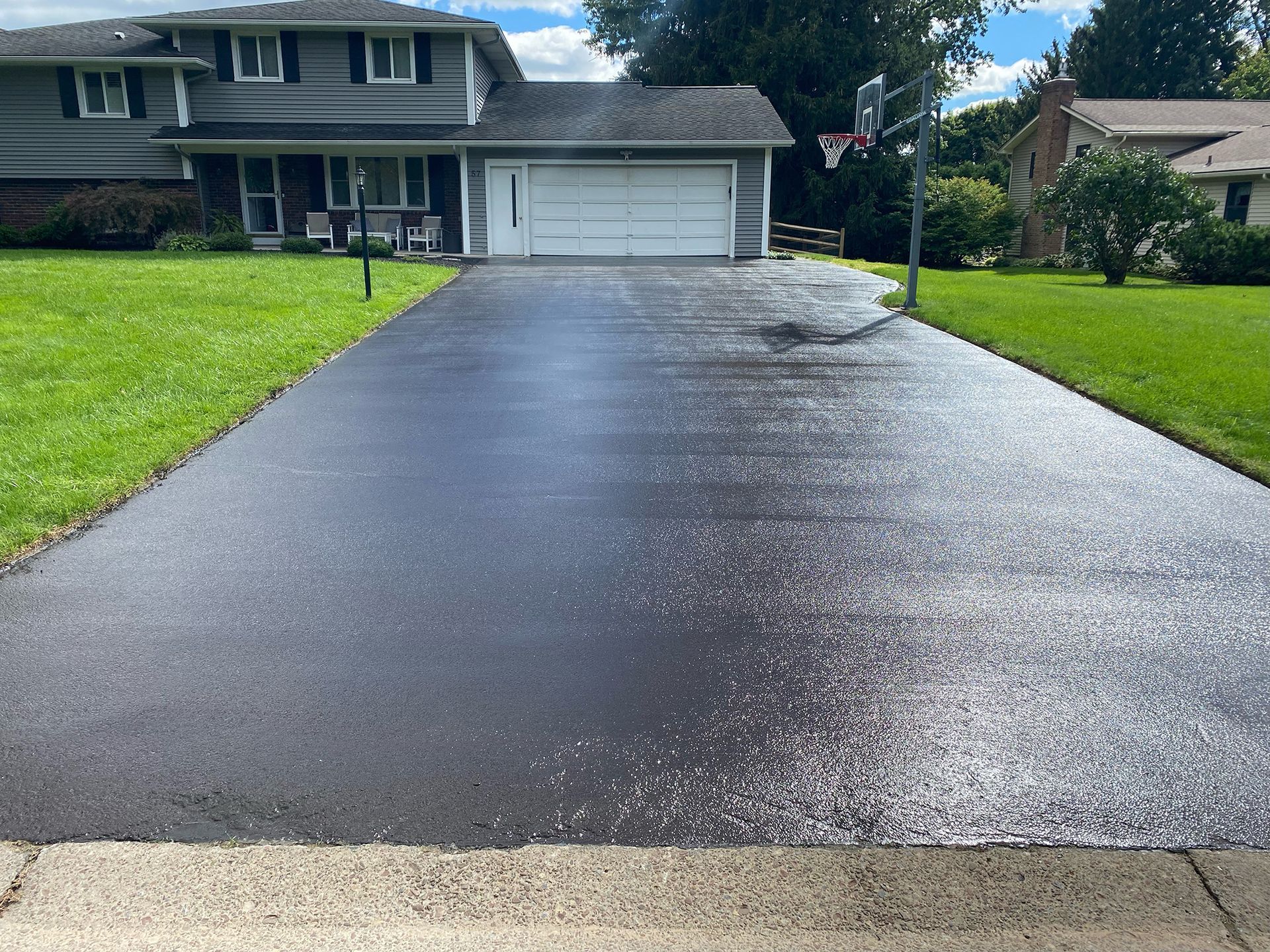 a black driveway leading to a house with a white garage door