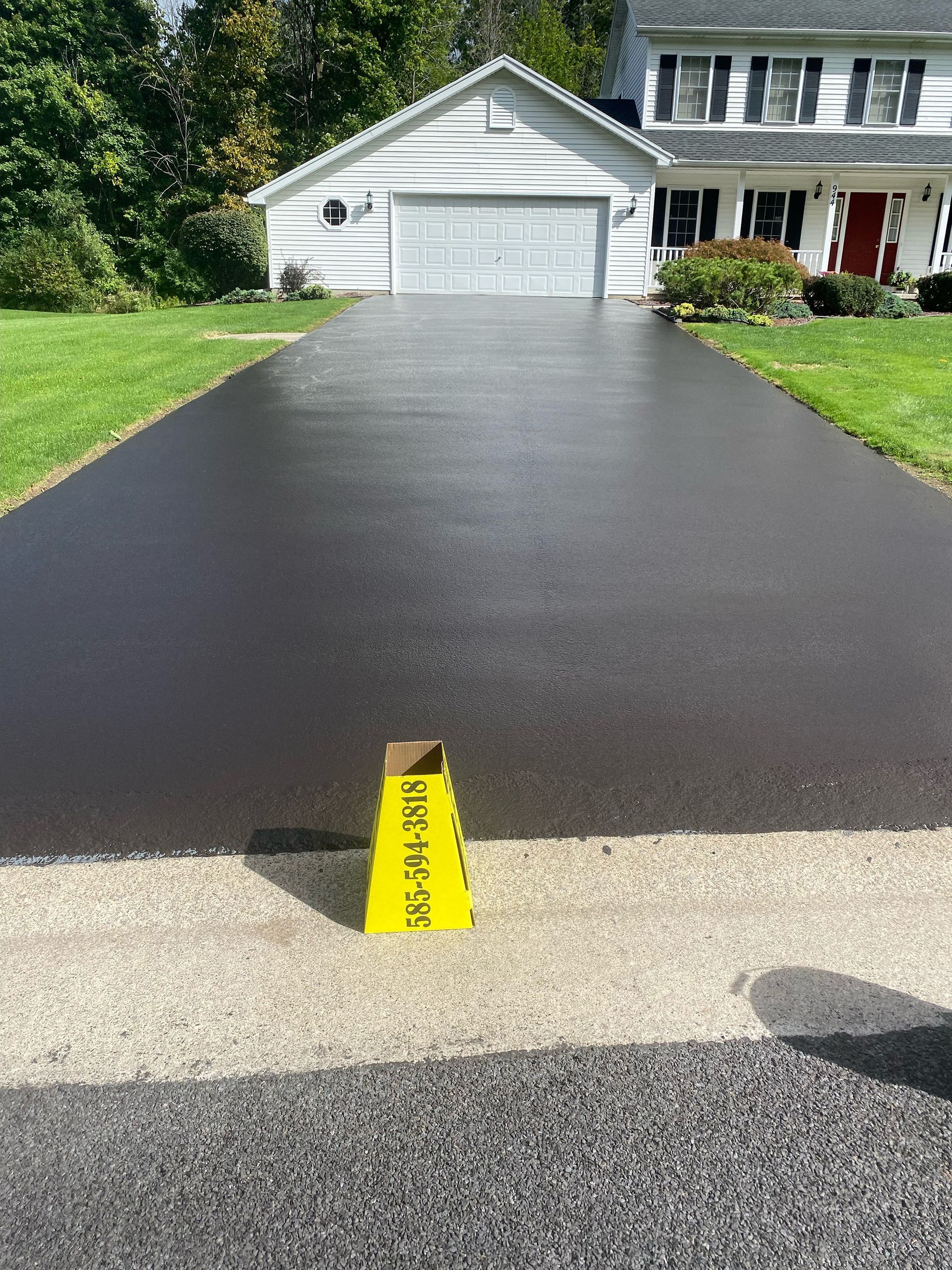 a black driveway with a yellow cone on the side of it in front of a house