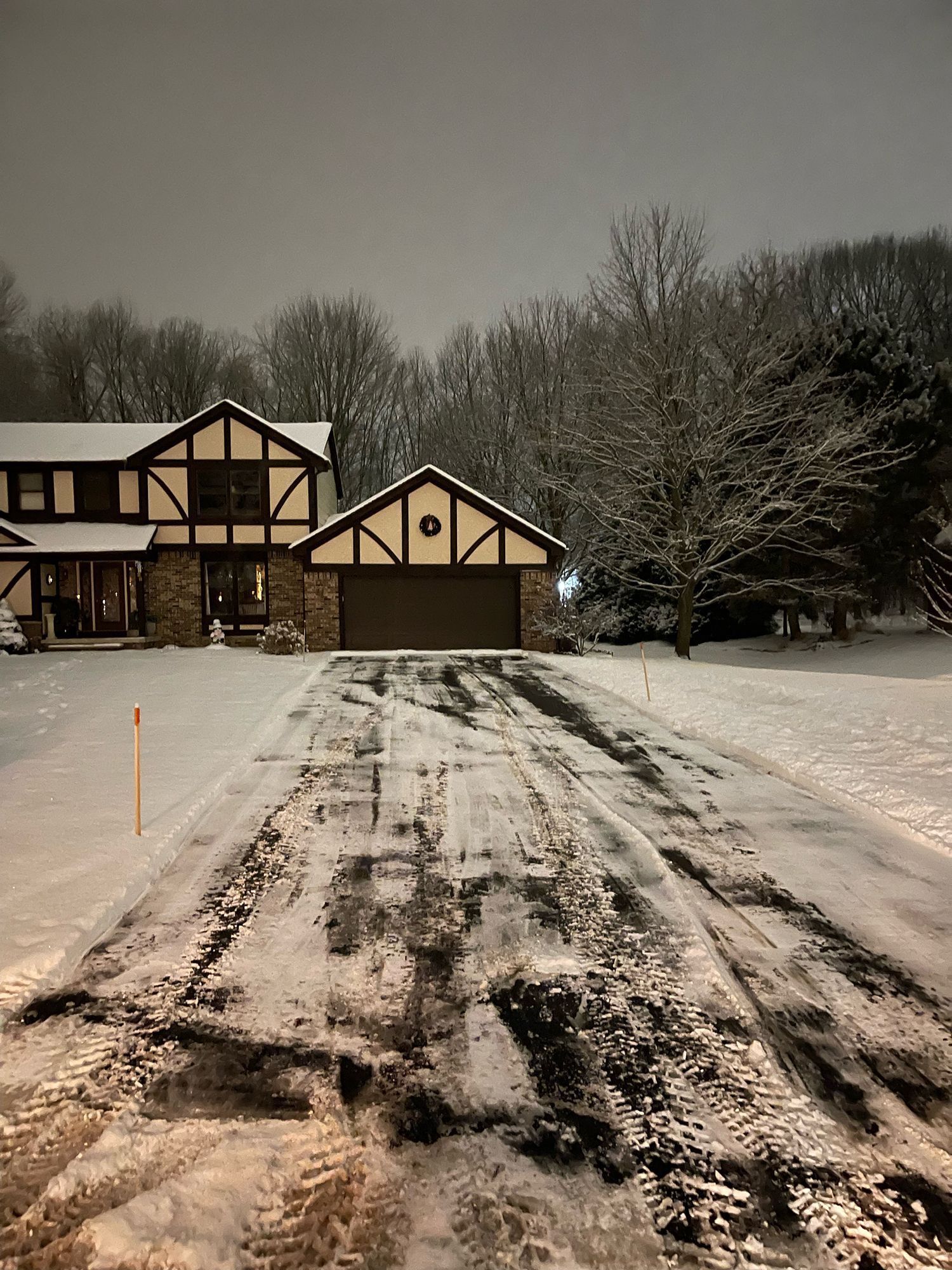 a snowy driveway leading to a house at night