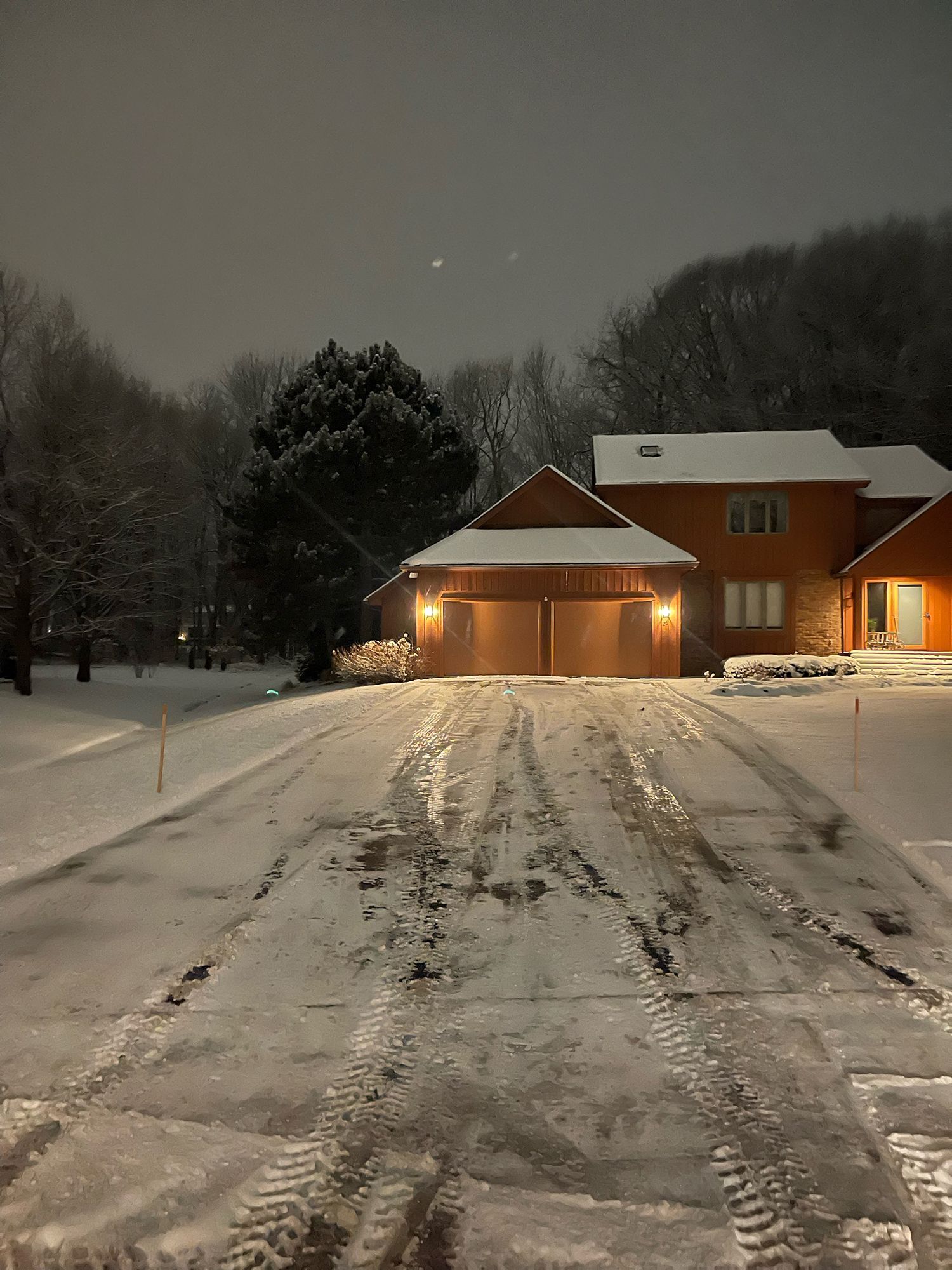 a snowy driveway leading to a house at night