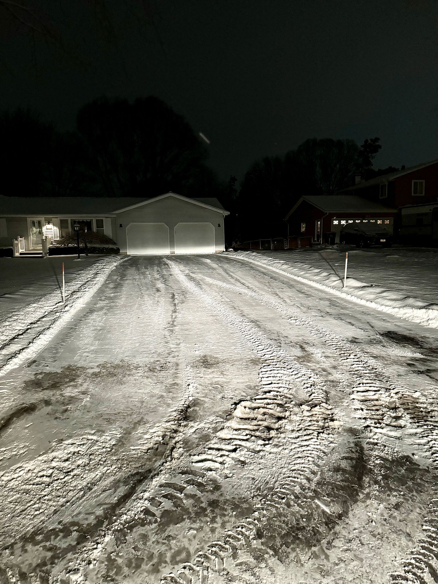 a black and white photo of a snowy driveway at night