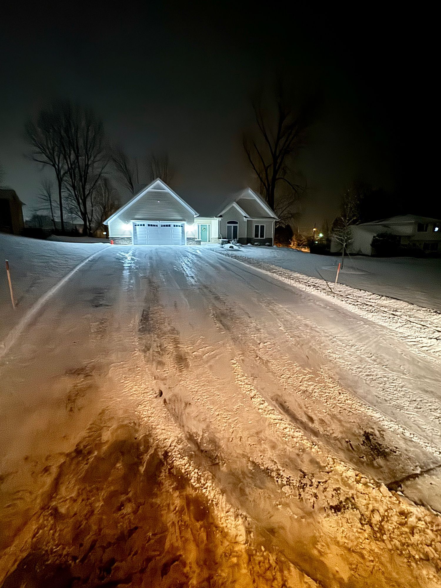 a snowy driveway leading to a house at night