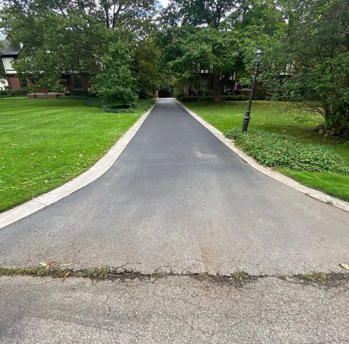 a driveway leading to a house surrounded by trees and grass