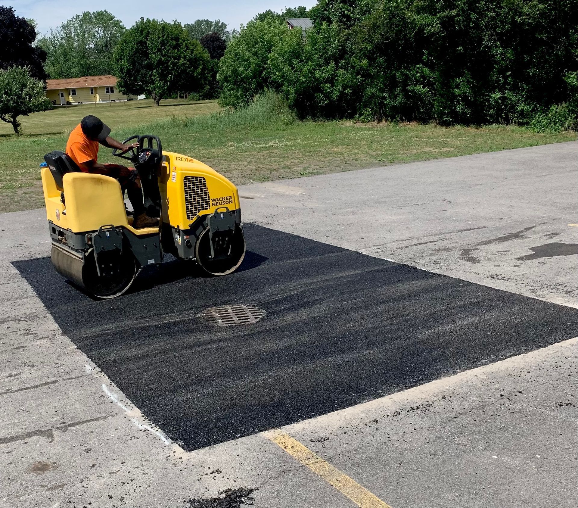 a man is driving a yellow roller on a parking lot