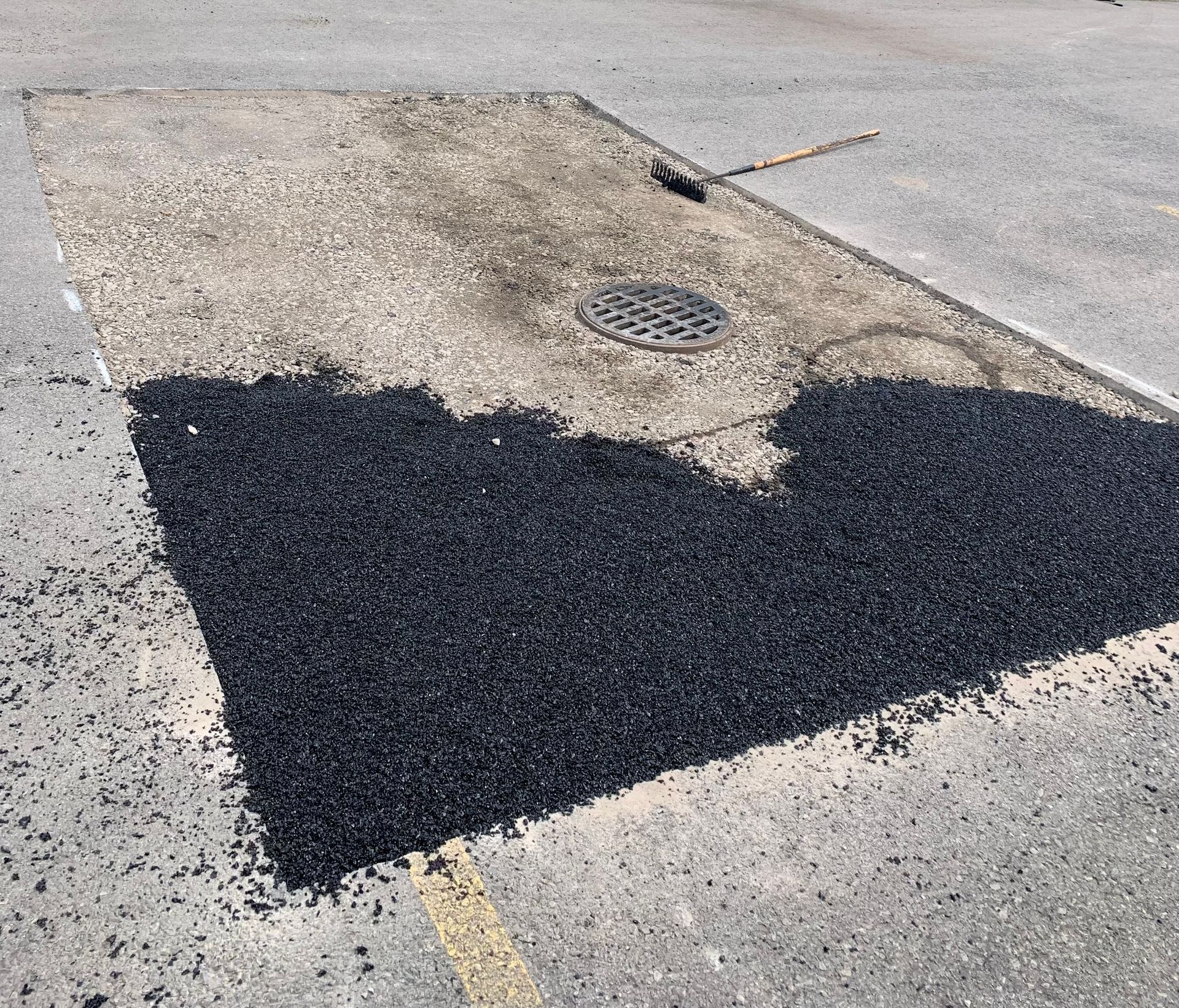 a patch of black asphalt is being spread on a concrete surface