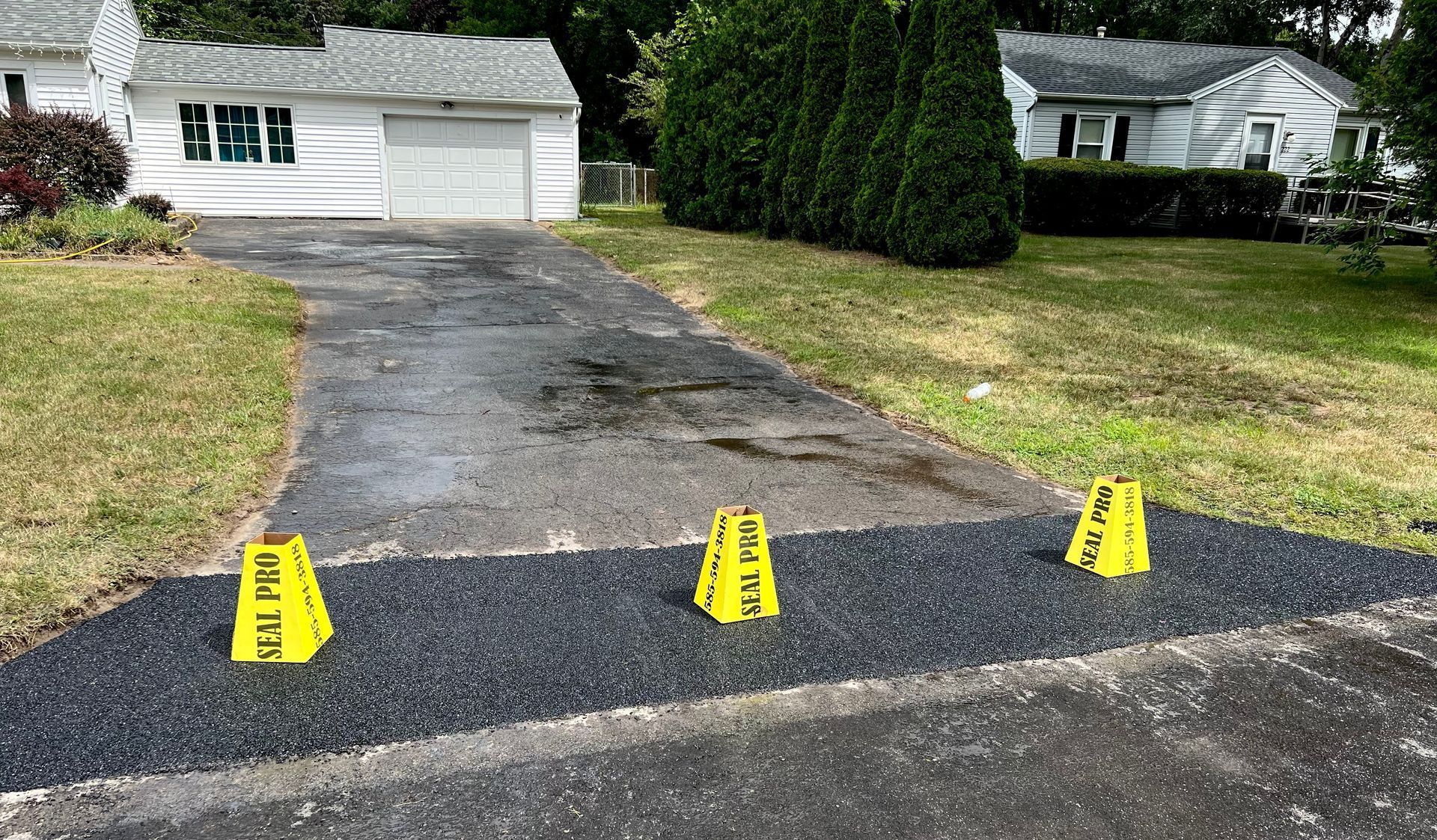 three yellow cones are sitting on the side of a driveway in front of a house
