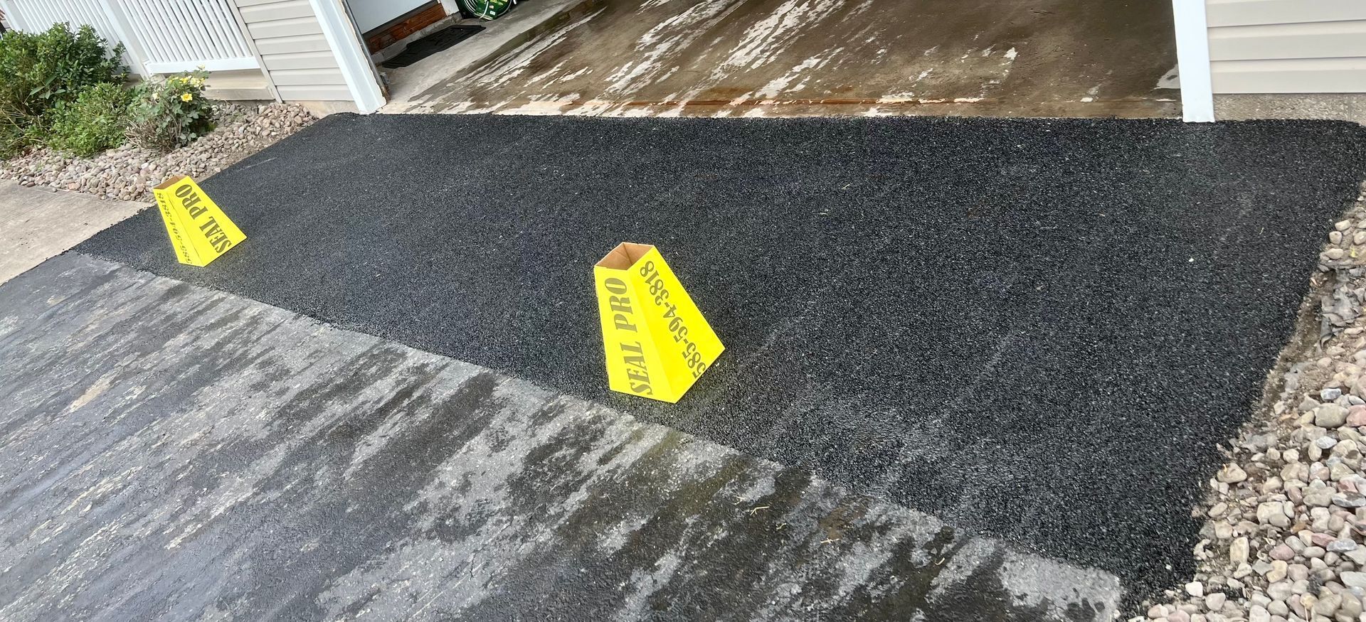 two yellow signs are sitting on top of a black asphalt driveway