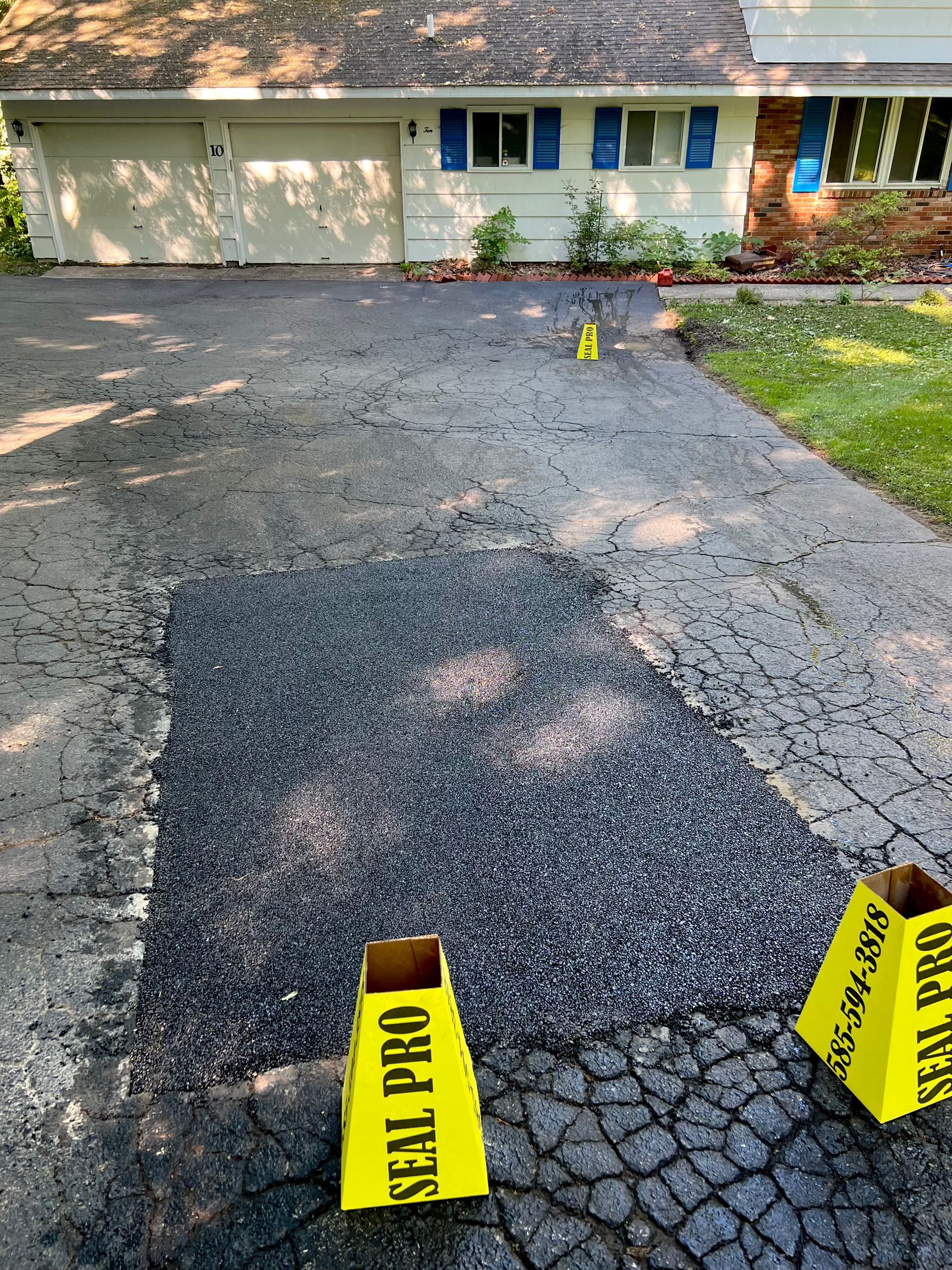 a house with a driveway that is being sealed with a seal pro sign