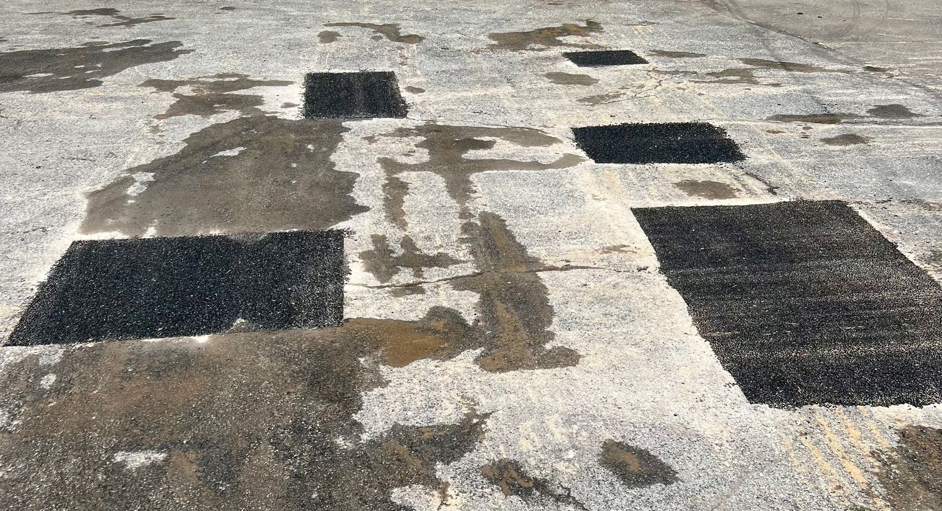 a close-up of a concrete floor with black asphalt on it