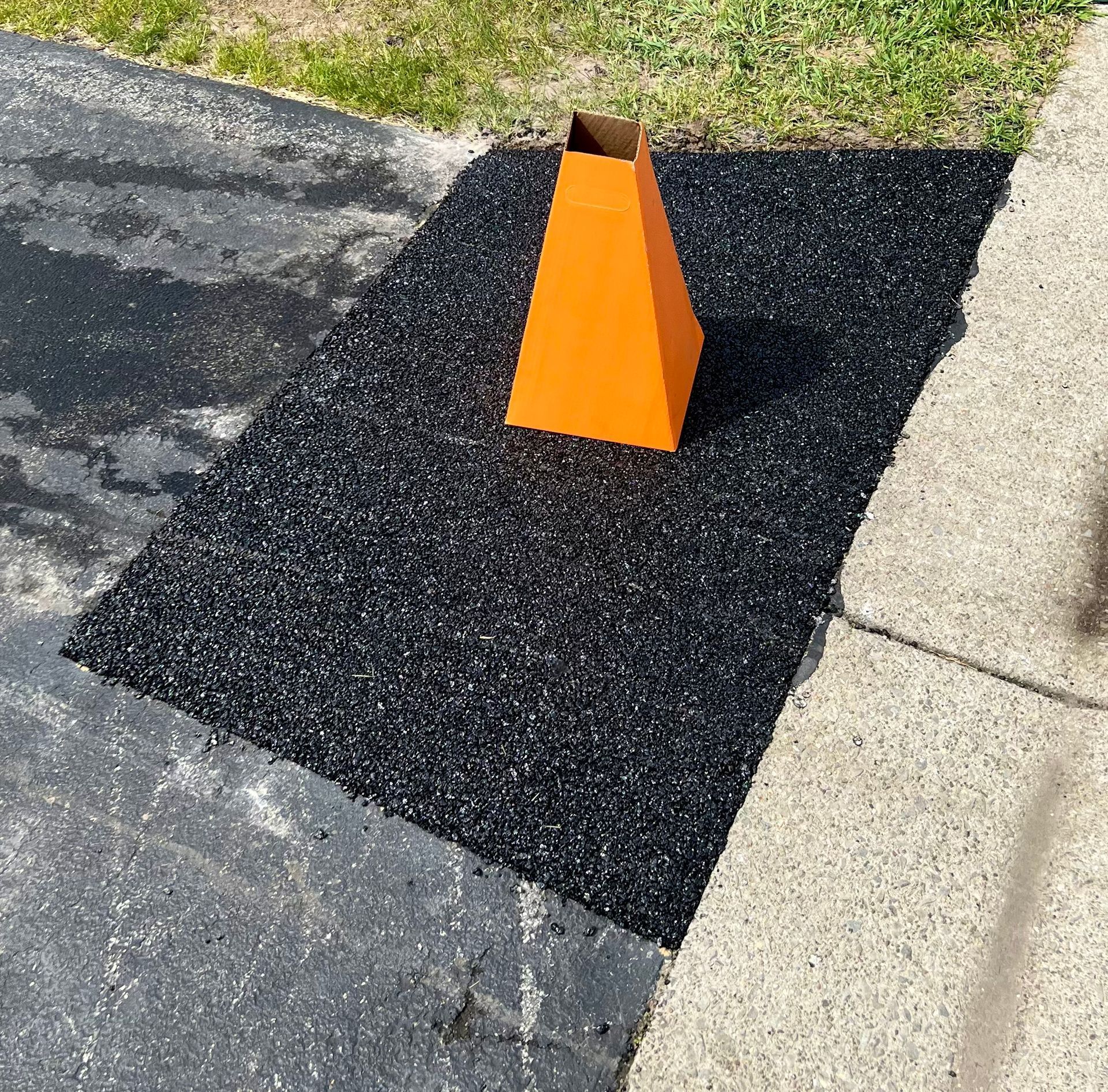 an orange cone is sitting on an asphalt