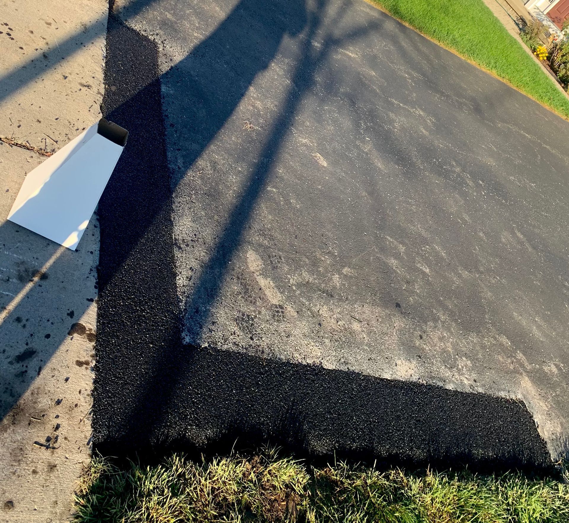 a corner of a driveway with a shadow on the ground