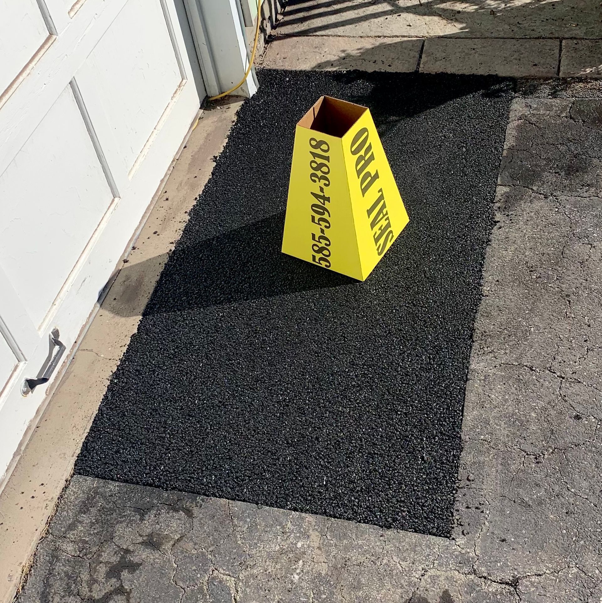 a yellow cone with a phone number on it is sitting on a black mat