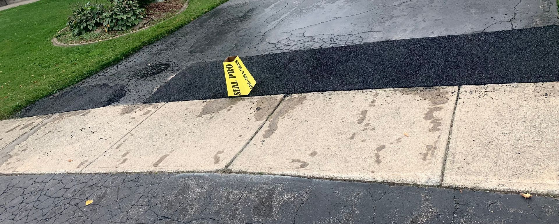 a yellow caution sign is sitting on the sidewalk next to a driveway