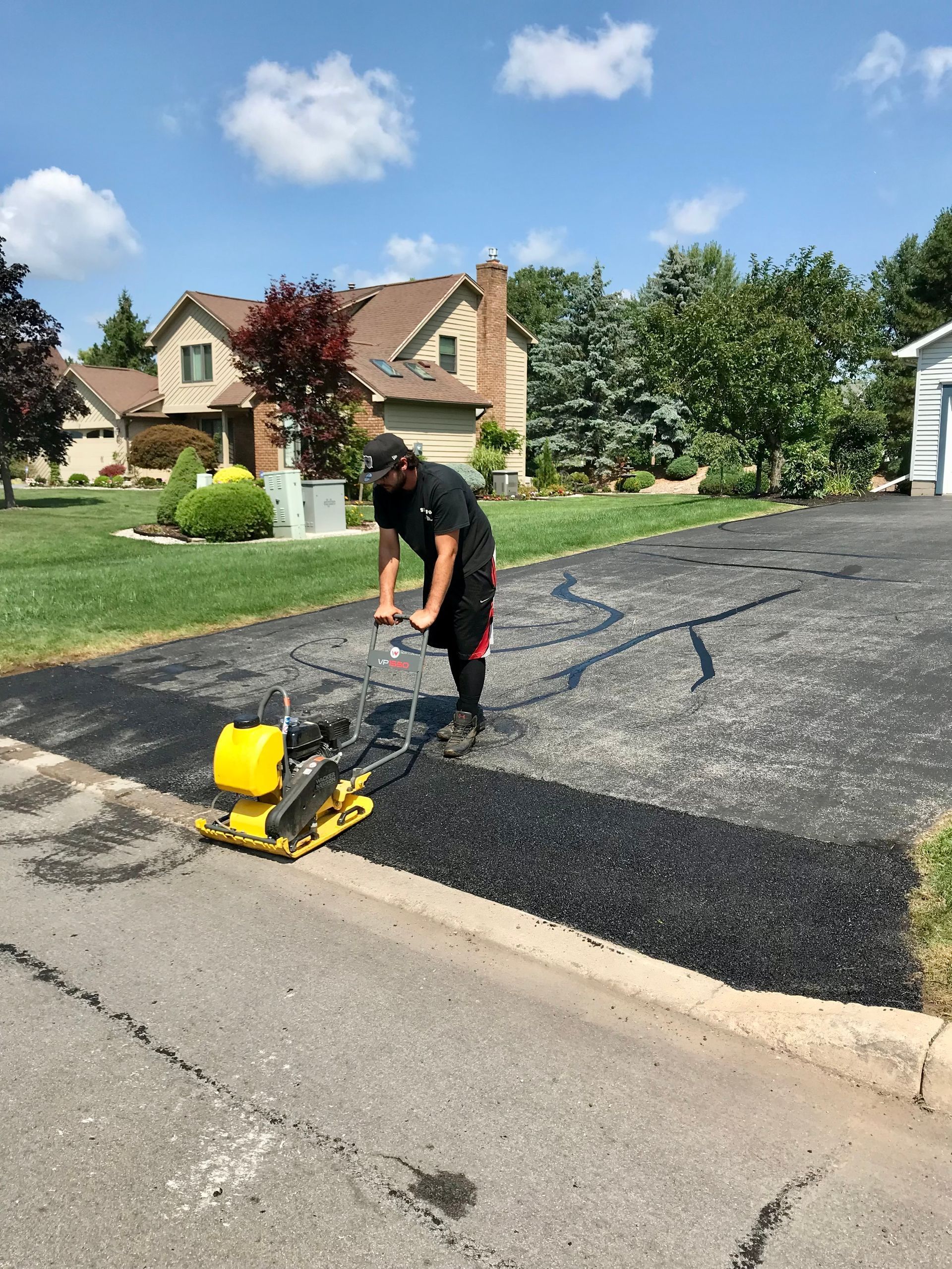 a man is working on a driveway in front of a house
