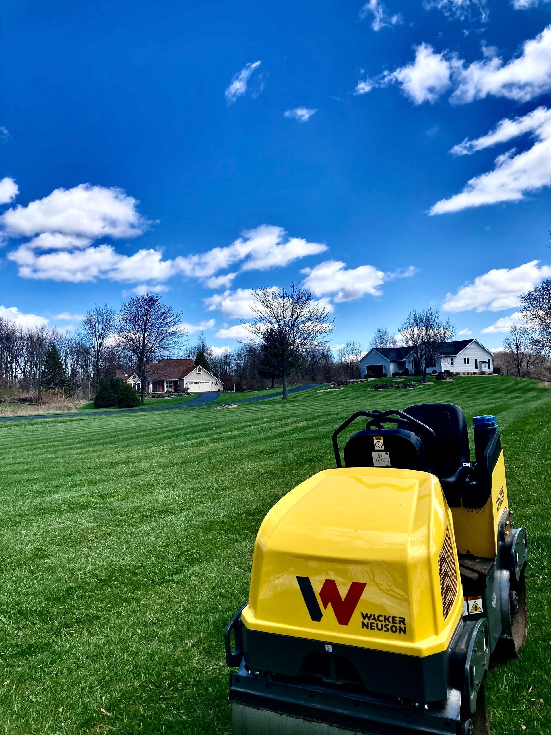 a yellow roller is parked in the middle of a lush green field
