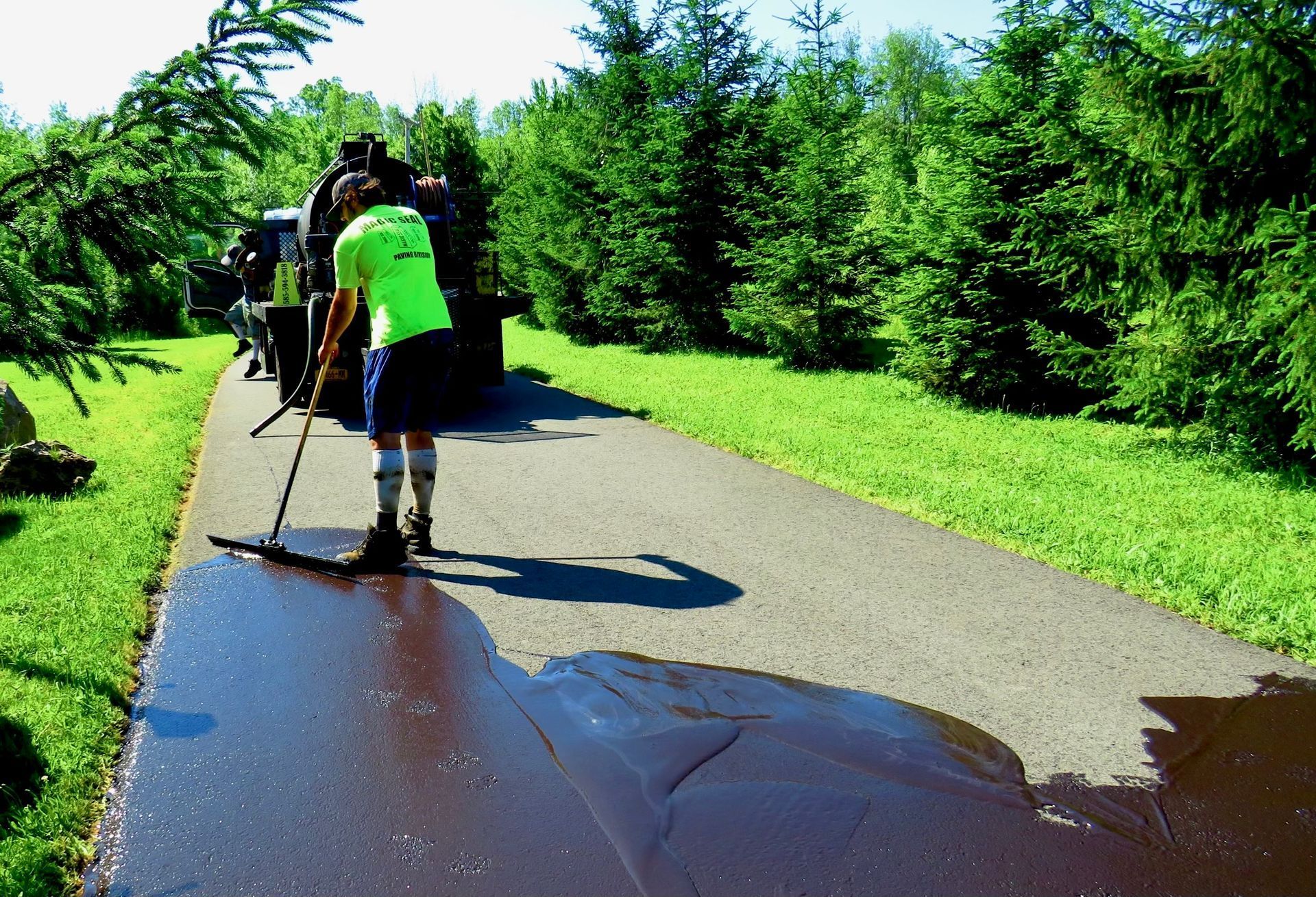 a man in a green shirt is spreading asphalt on a road