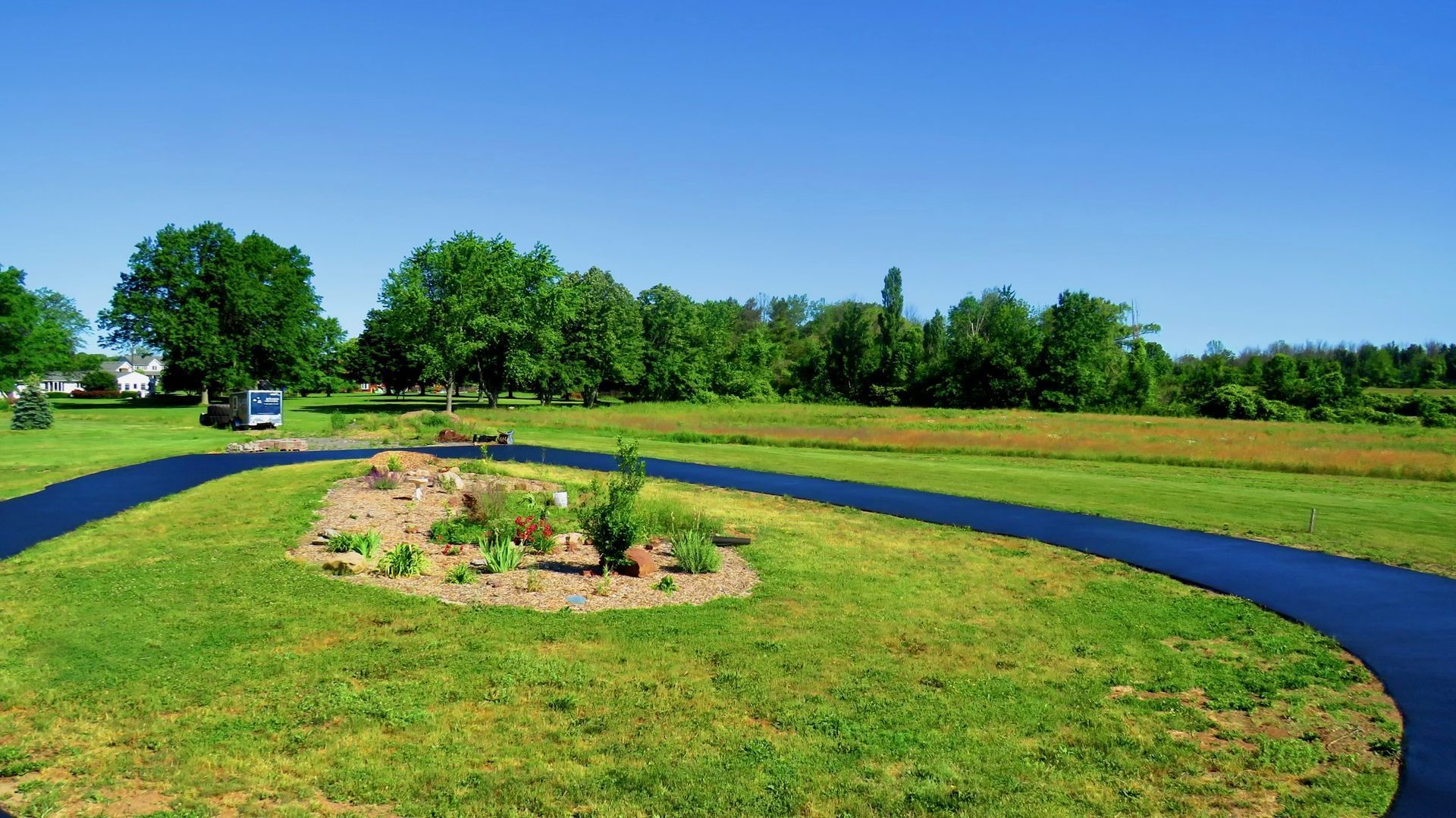 a black road is going through a lush green field