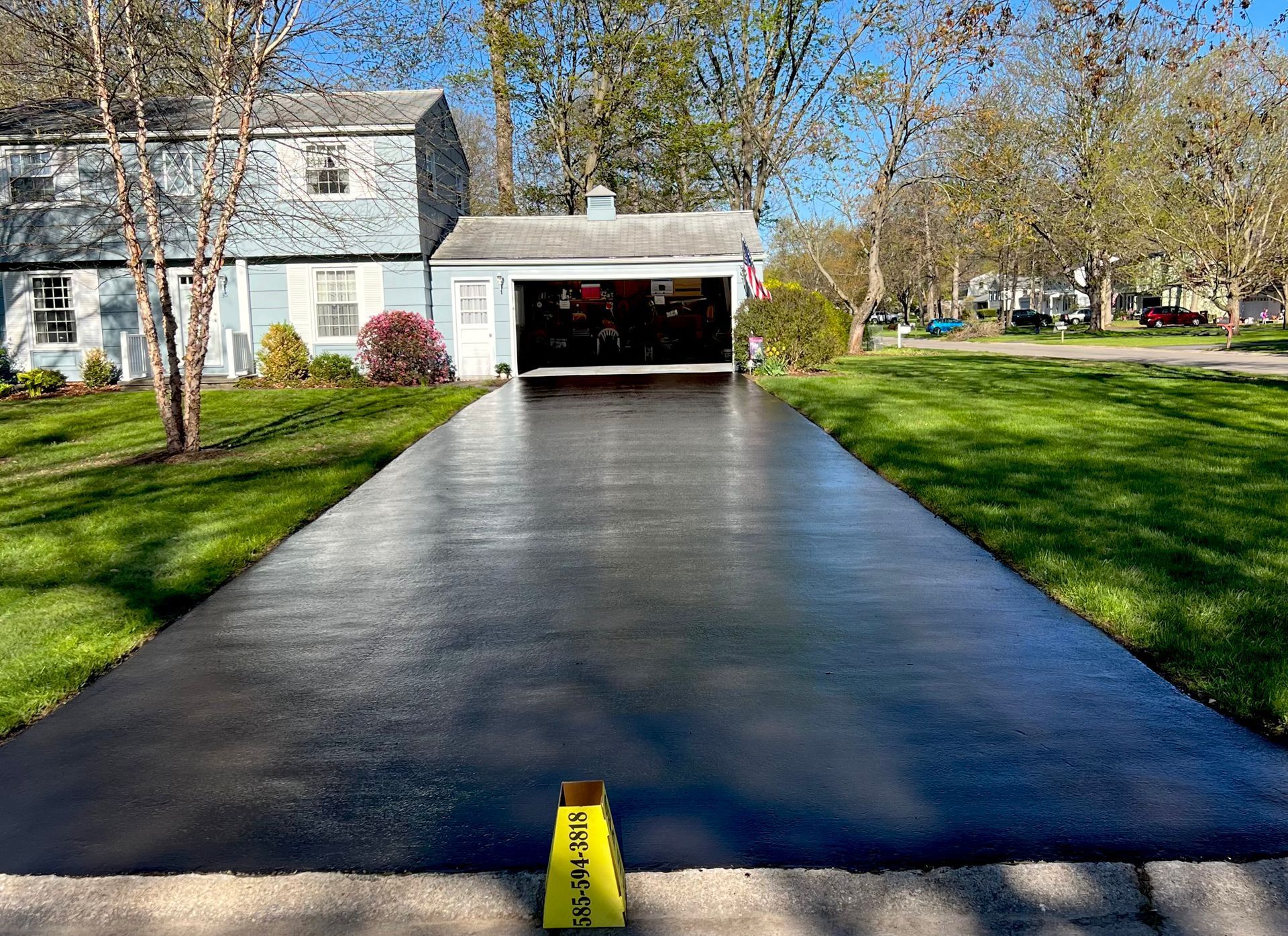 a black driveway with a yellow caution sign on the side of it leading to a house