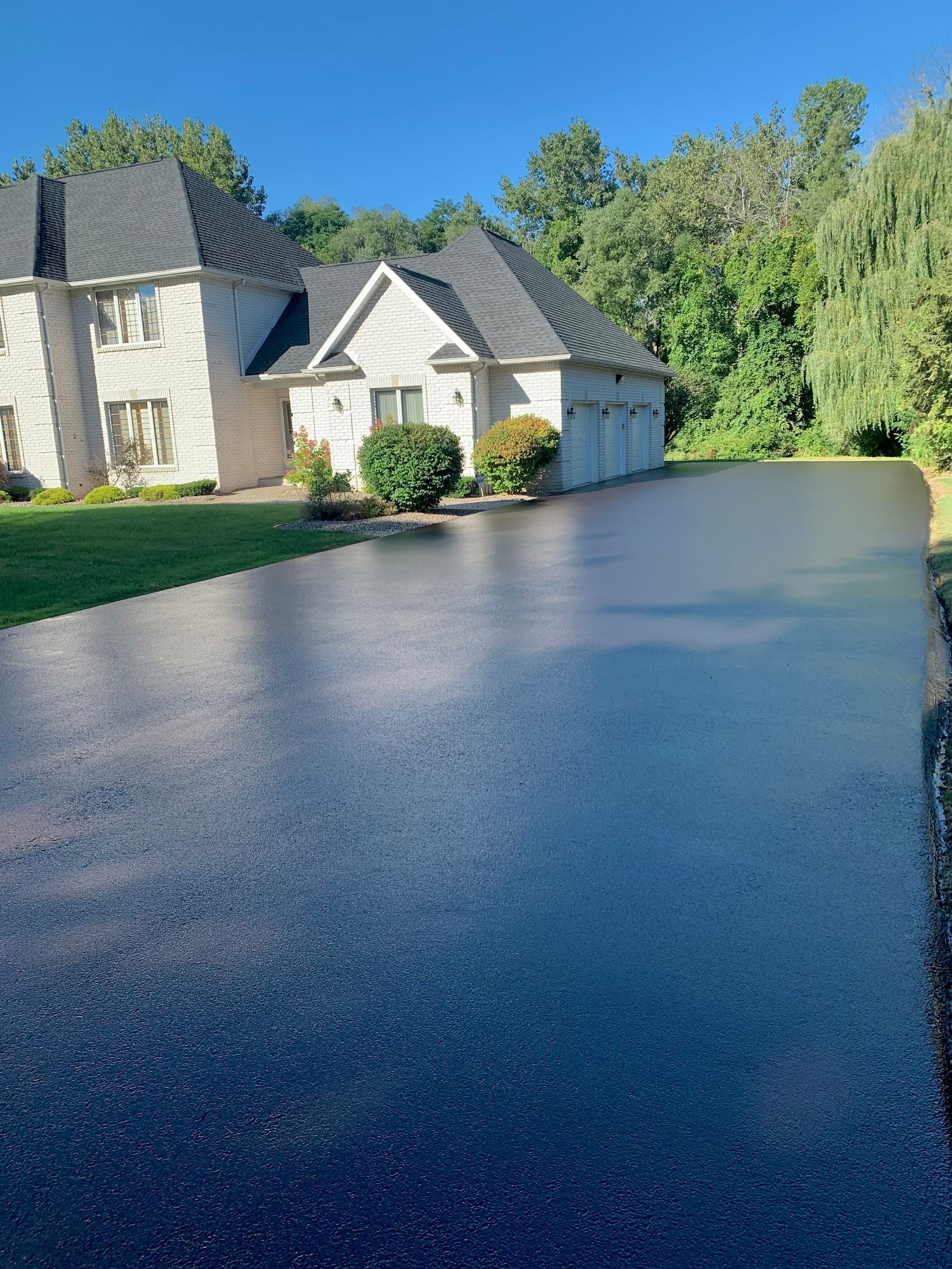 a large white house with a black driveway in front of it