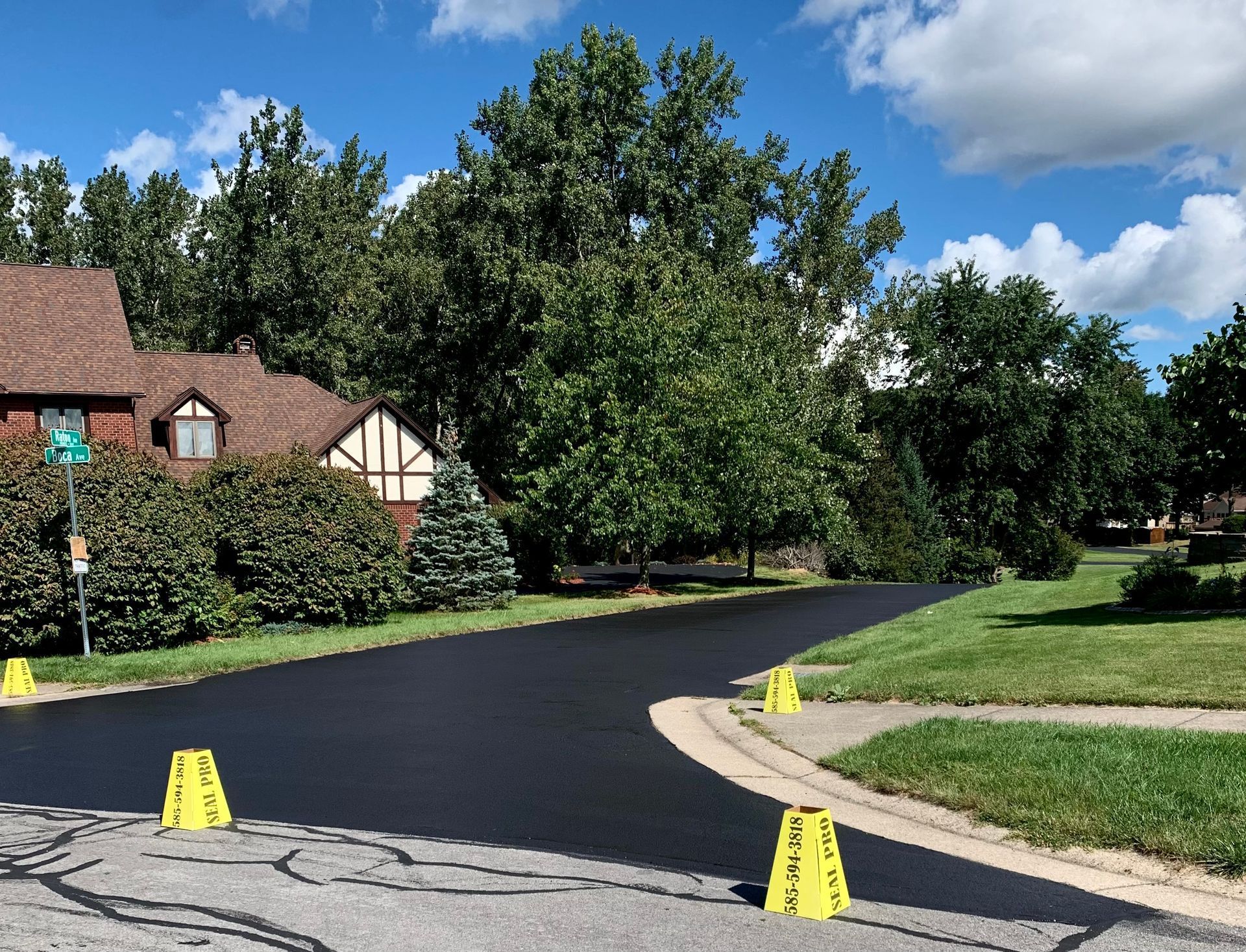 a driveway with a house in the background and yellow cones on the side of it