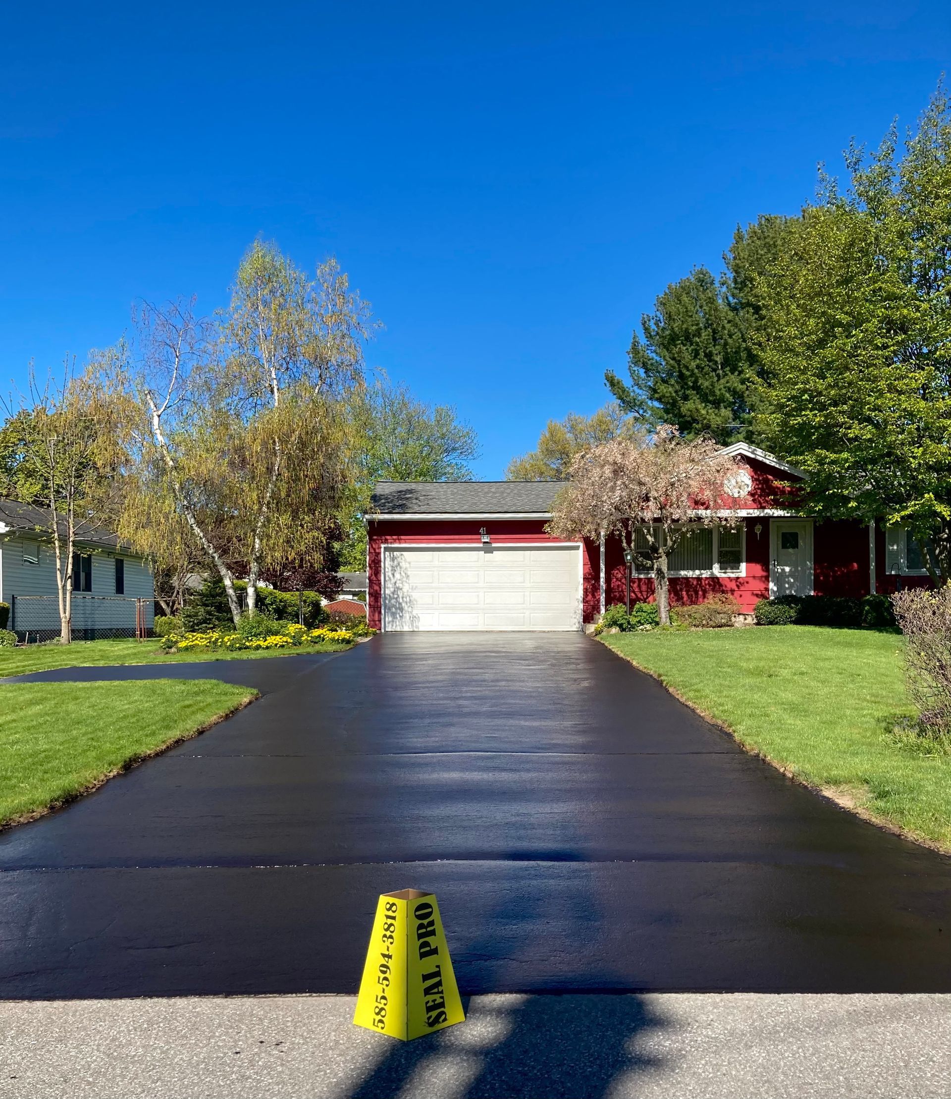 a black driveway with a yellow caution cone in front of a house
