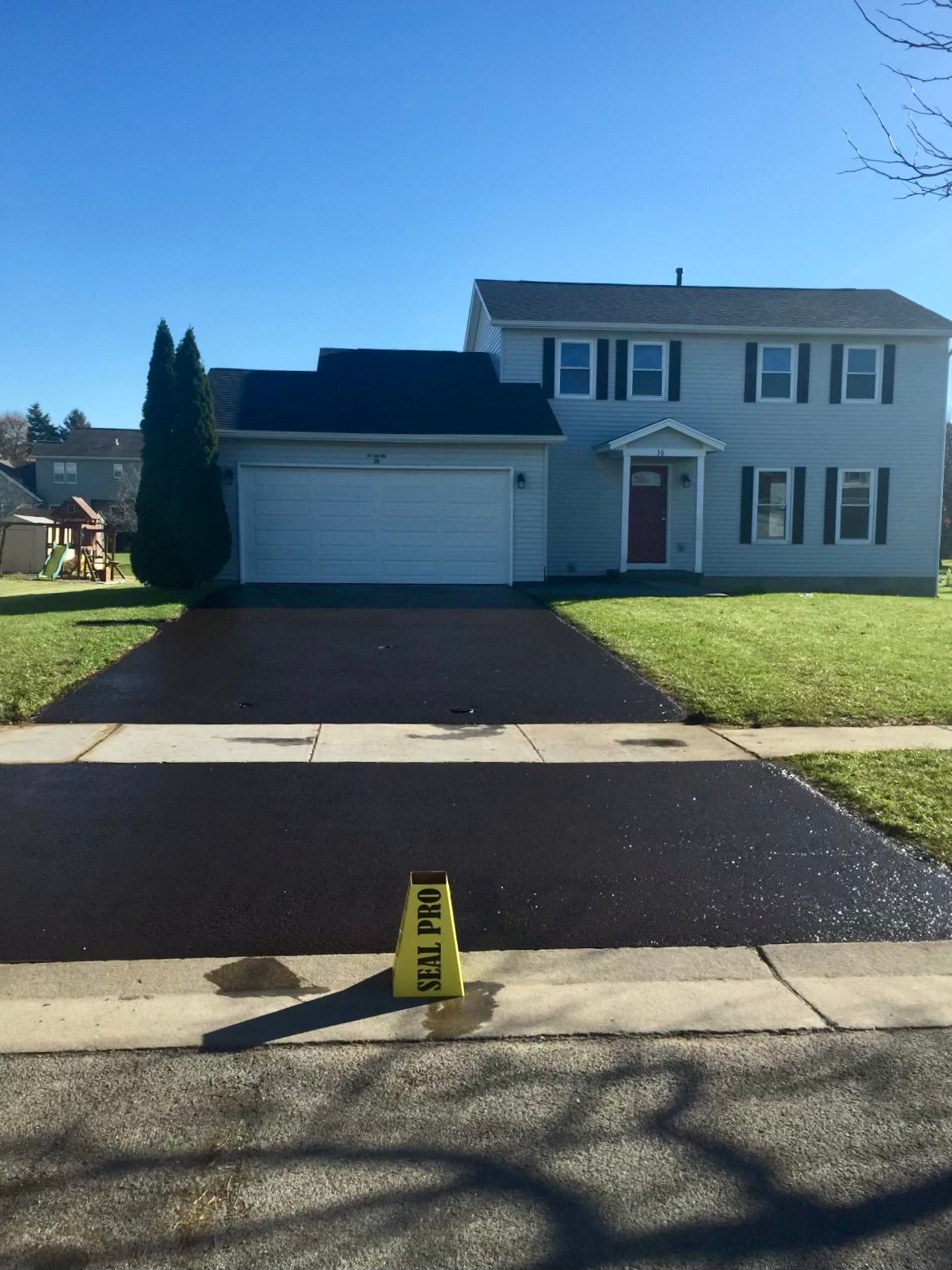 a house with a black driveway and a yellow caution cone
