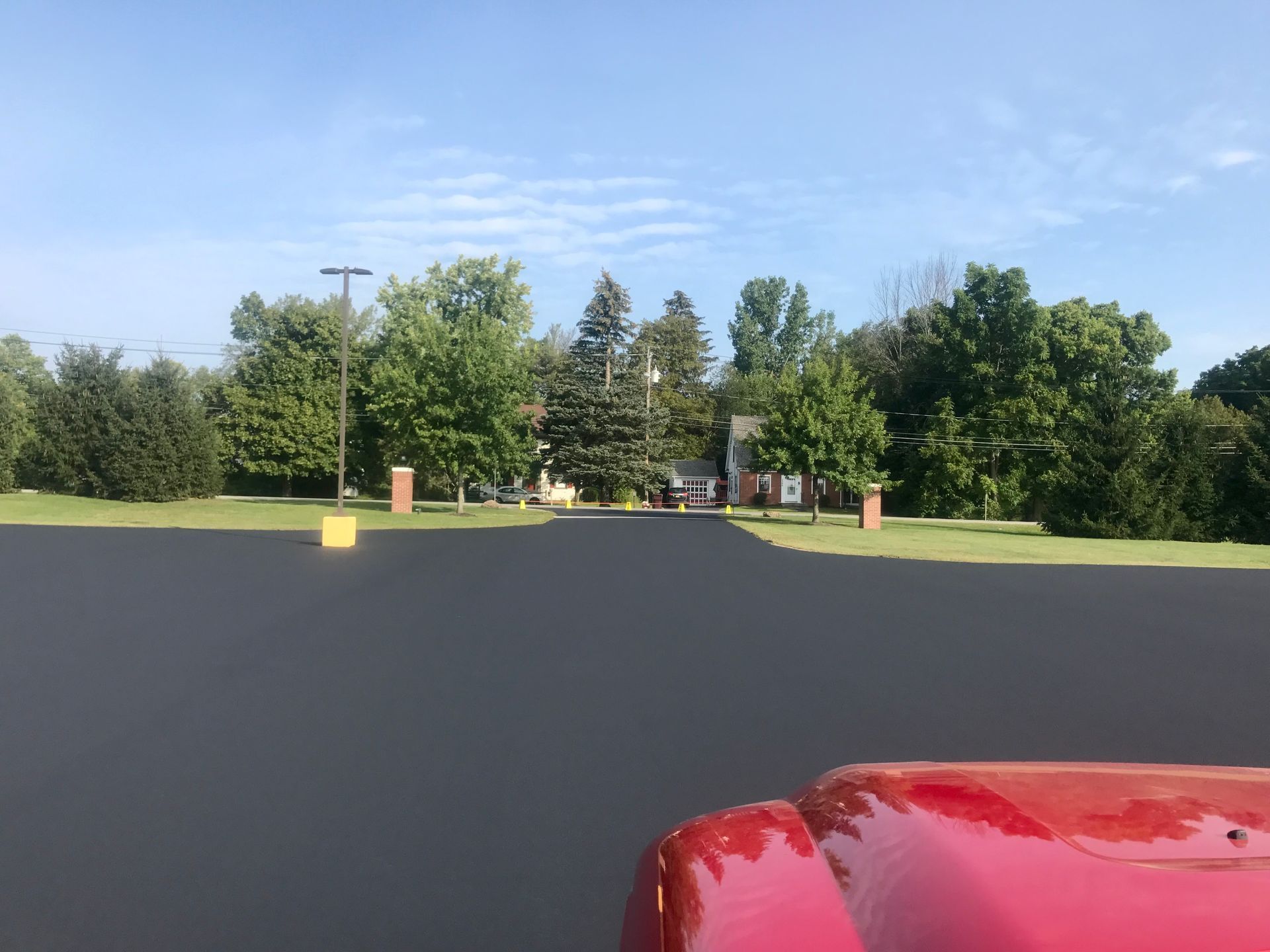 a red car is parked in a parking lot with trees in the background