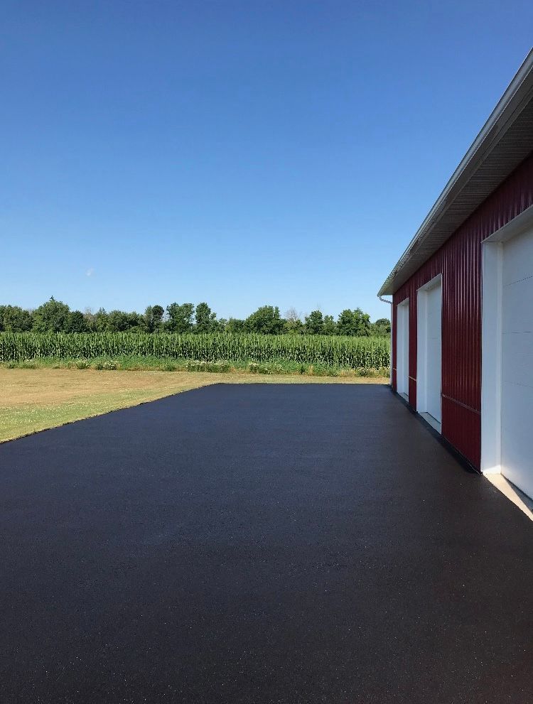 a red barn with a black driveway in front of it