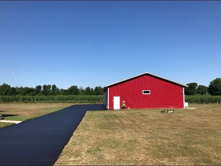 a large red barn is sitting in the middle of a grassy field