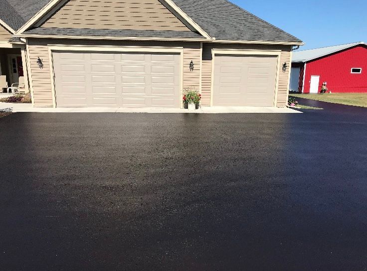 a house with two garage doors and a black driveway in front of it