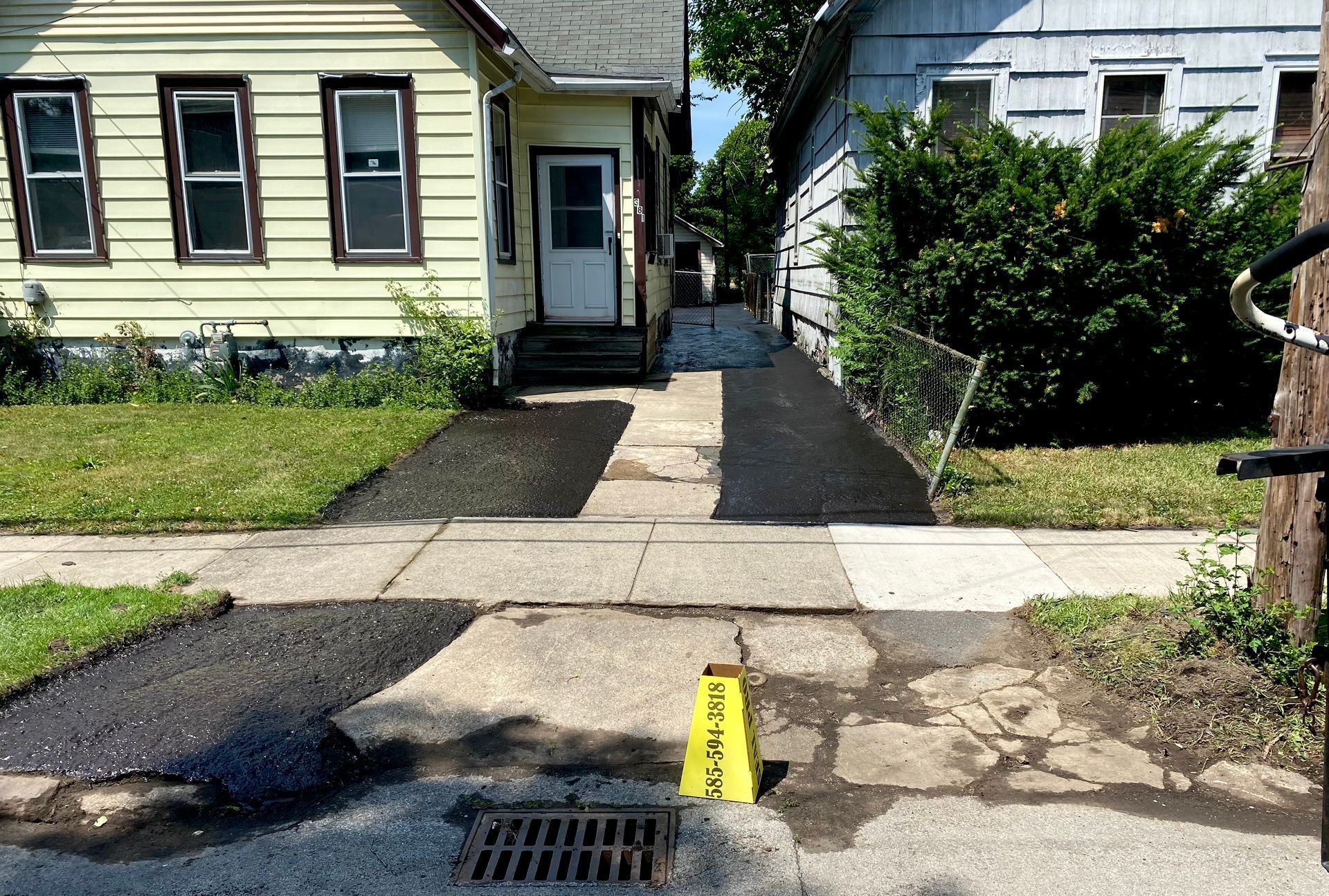 a yellow caution sign is on the sidewalk in front of a house