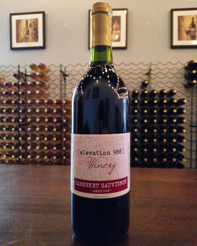 A bottle of elevation 965 winery cabernet sauvignon sits on a wooden table