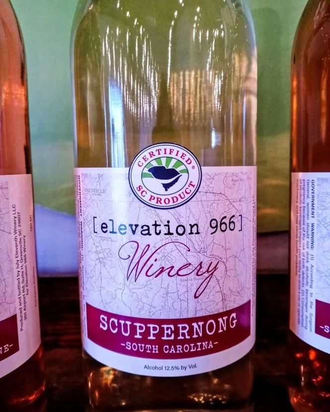 Three bottles of elevation 966 winery scuppernong sit on a shelf