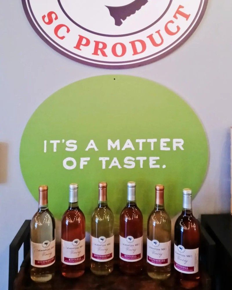 Bottles of wine are lined up under a sign that says it 's a matter of taste