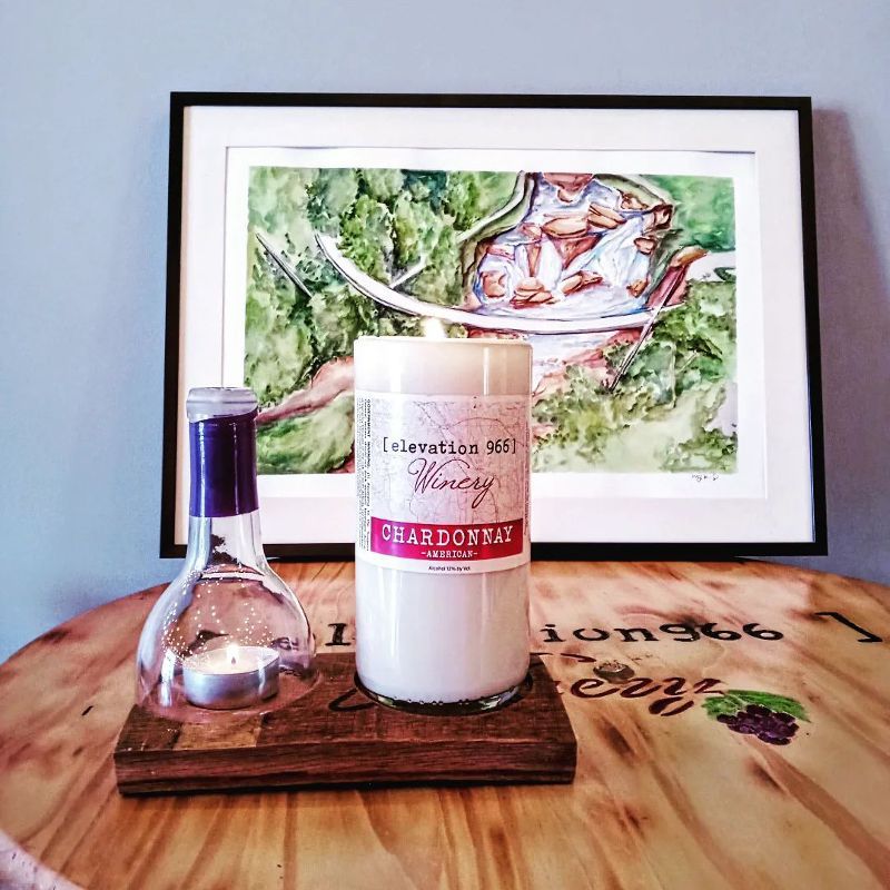 A candle is sitting on a wooden table in front of a painting.