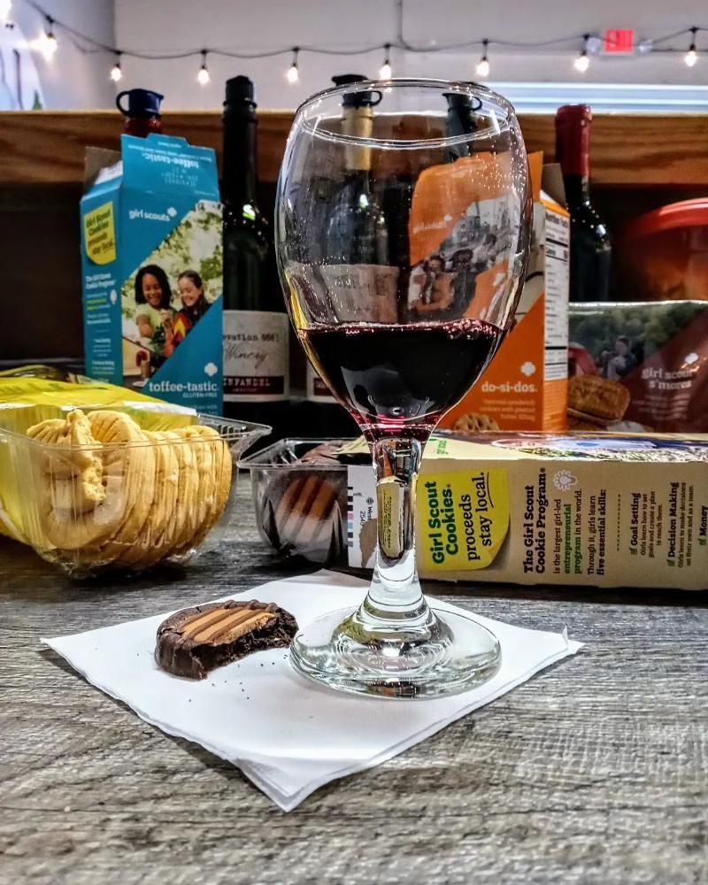 A glass of wine is sitting on a napkin next to a box of crackers.