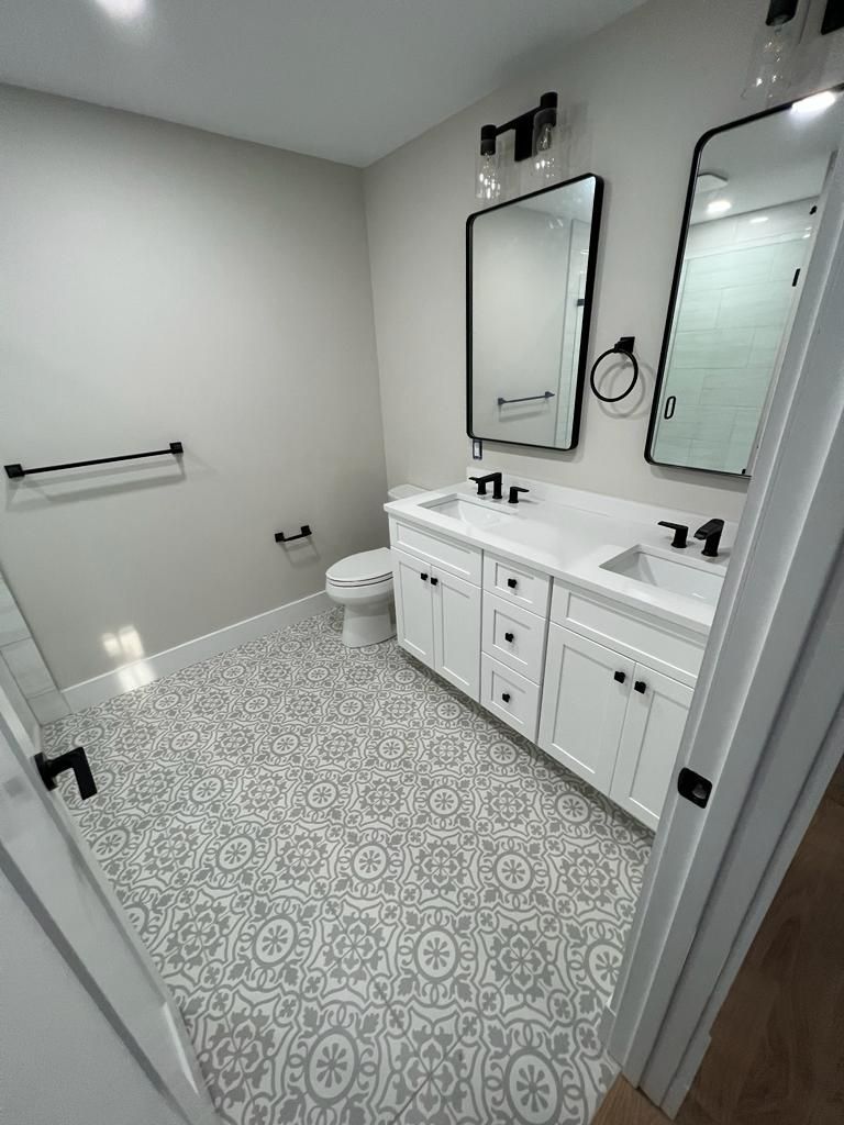 a bathroom with two sinks, a toilet, and two mirrors