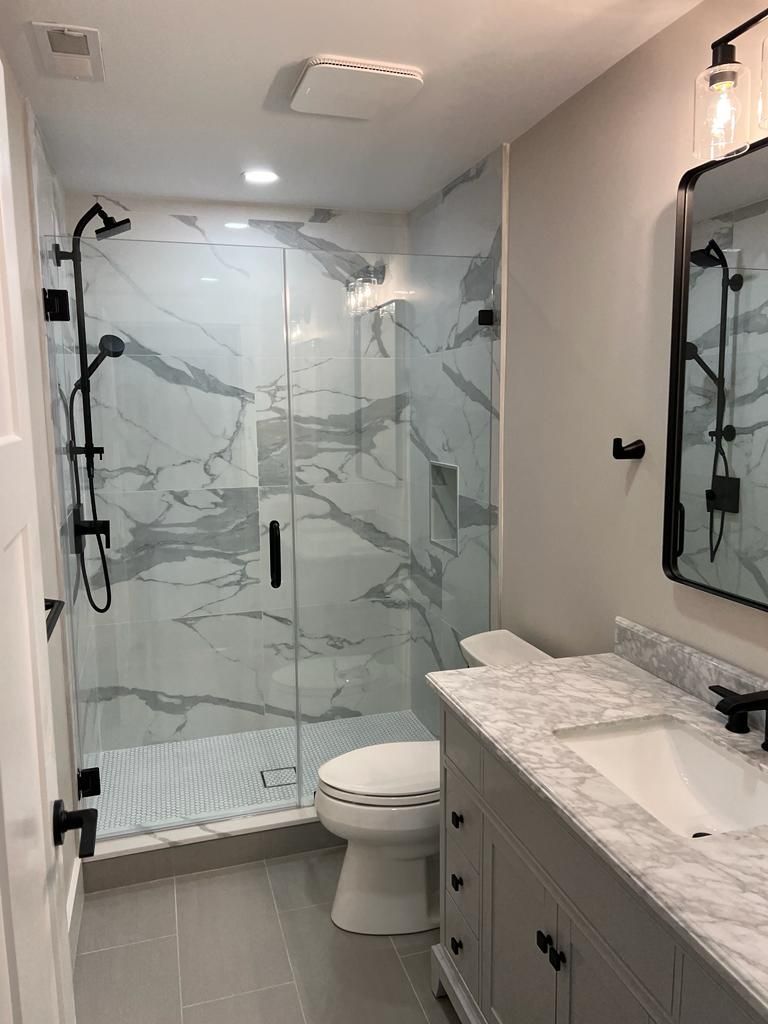 a bathroom with a toilet, sink, shower and mirror