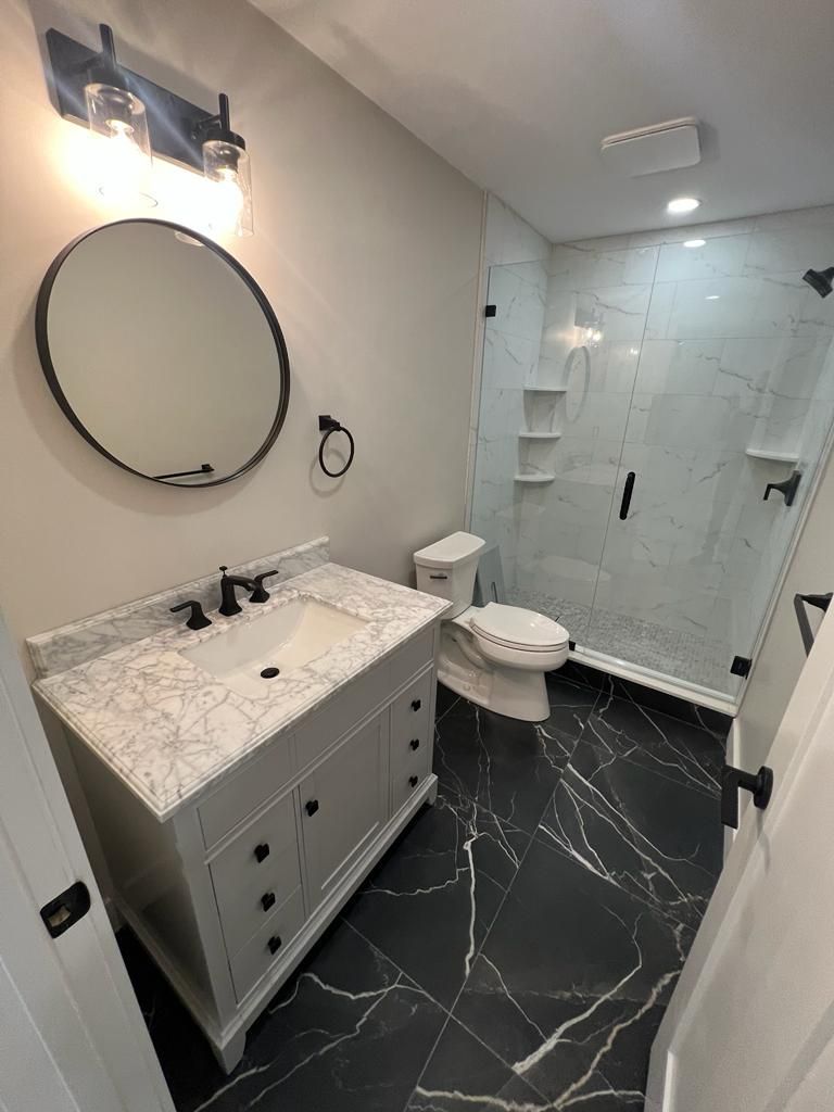 a bathroom with a sink, toilet, shower and mirror