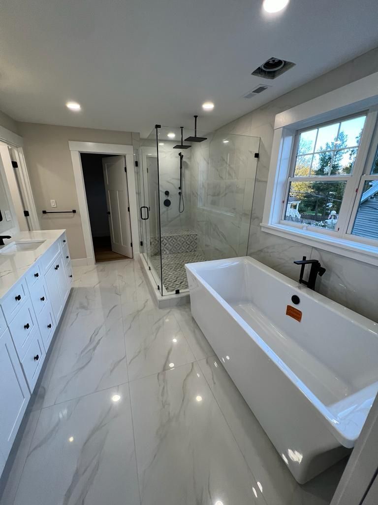a bathroom with a tub, sink, shower and window