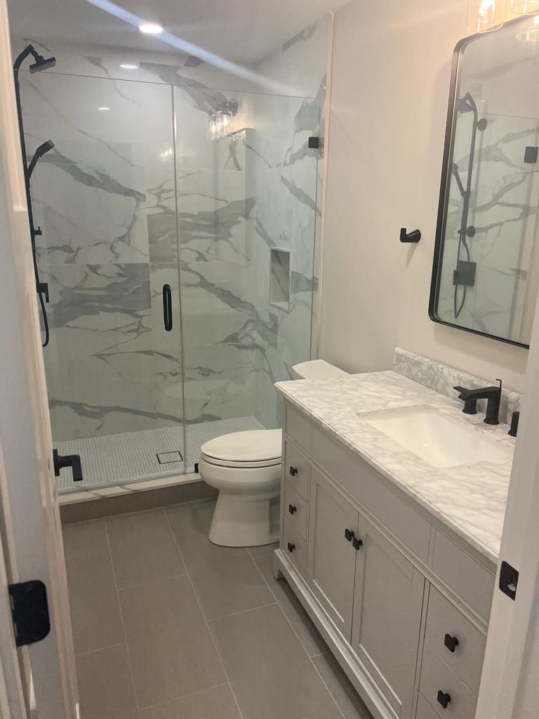 a bathroom with a toilet, sink, shower and mirror