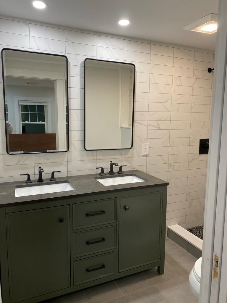 a bathroom with two sinks, two mirrors and a toilet