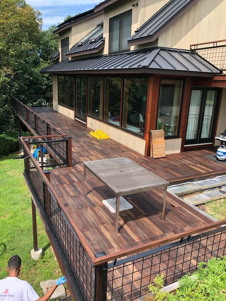 a man is painting a wooden deck in front of a large house