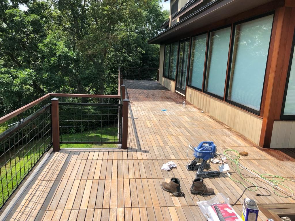 a wooden deck with a railing and trees in the background