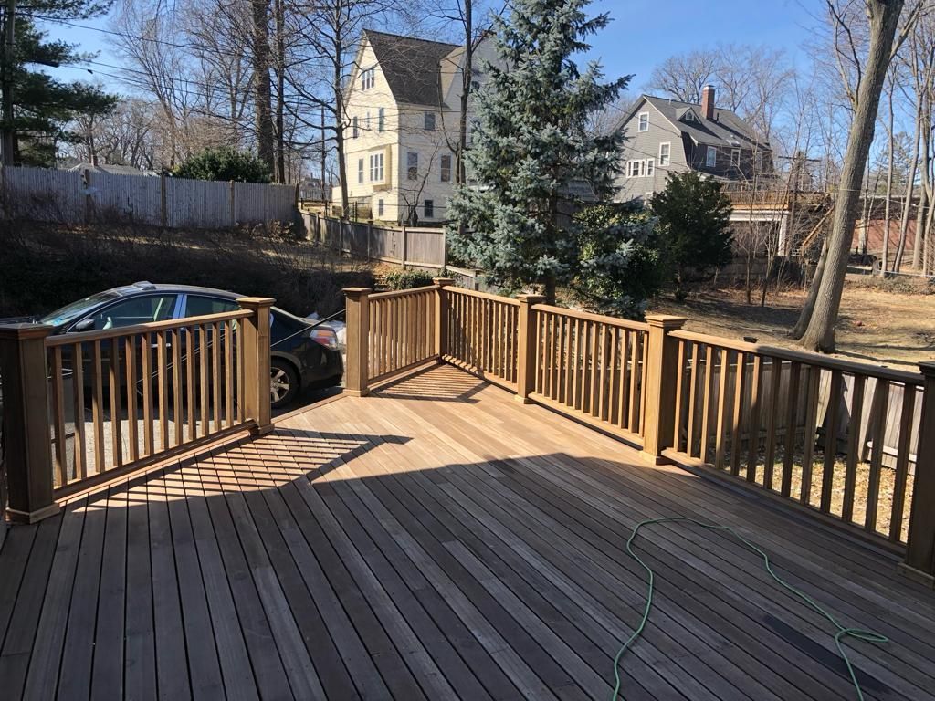 a wooden deck with a car parked on it and a house in the background
