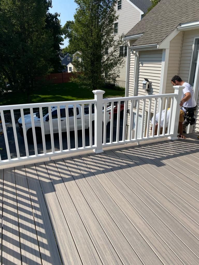 a man is standing on a deck next to a white railing