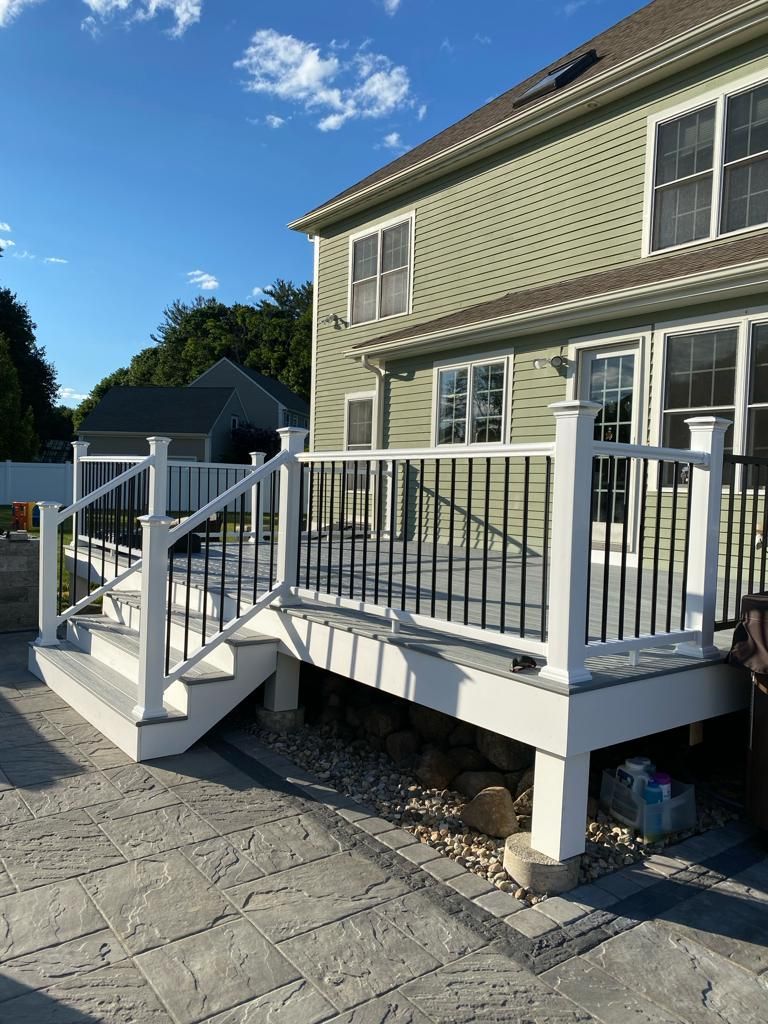 a white deck with stairs and a black railing is in front of a house
