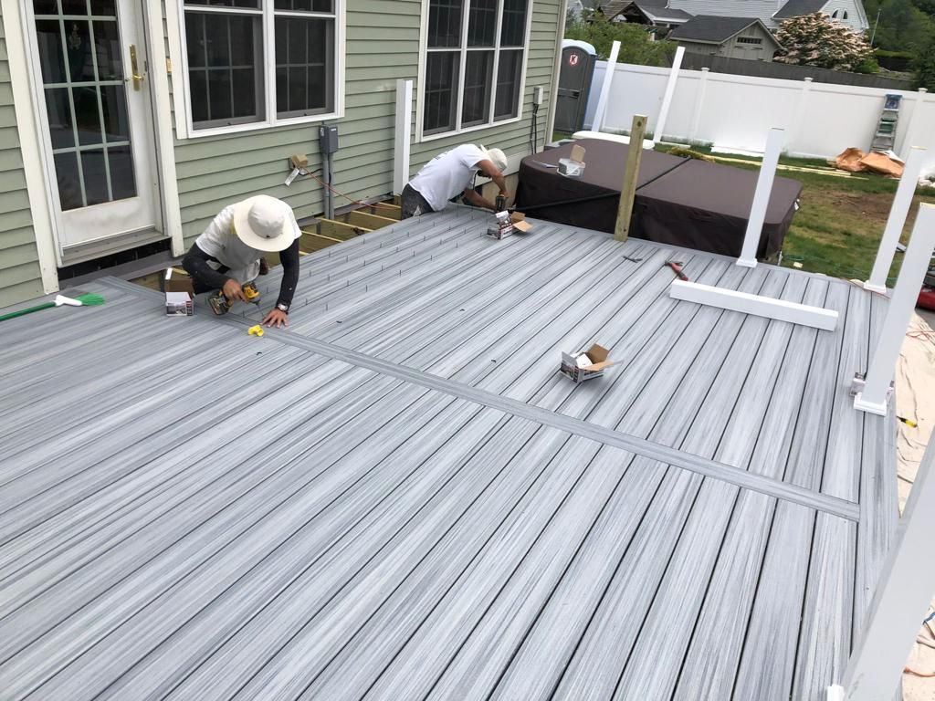 two men are working on a deck in front of a house